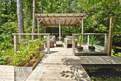 a wooden boardwalk with a pergola in a garden at Cedar and Salt in Tofino
