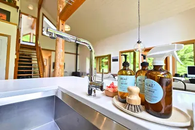 a kitchen counter with two bottles of alcohol and a sink at Cedar and Salt in Tofino