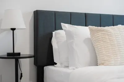a bed with white pillows and a table with a lamp at Honeyville House Sleeps 8 Pool Table in Edmonton