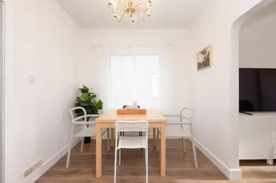 a dining room table with white chairs and a chandelier at Quiet 5 BR 7 bed Escape with sunny Deck near UBC in Vancouver