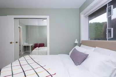 a bedroom with a white bed with a purple pillow at Luxury Modern 2-Bedroom Suite Near Transit & Shops in White Rock