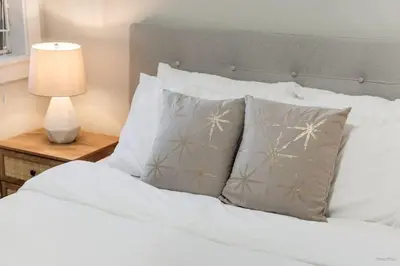 a bedroom with a bed with white sheets and pillows at Private Entrance Suite Near Deer Lake & Metro in Burnaby