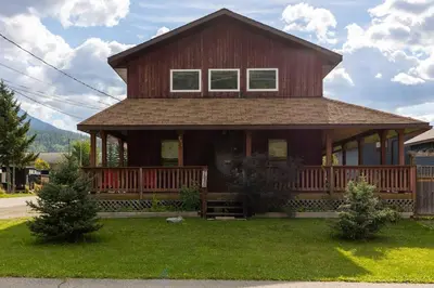 a large wooden house with a porch on a lawn at Huckleberry Lodge by Fernie Central Reservations in Fernie