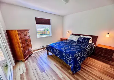 a bedroom with a bed and a dresser and a window at Harbourview Hideaway Sooke in Sooke