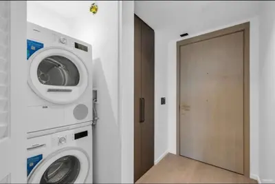 a laundry room with a washer and dryer next to a door at Modern Brand New 1-Bedroom Condo in Downtown in Vancouver