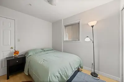 a white bedroom with a bed and a lamp at Modern & Bright 5BR Family Home in Vancouver