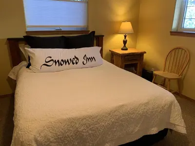 a bedroom with a white bed with a pillow on it at Snowed Inn Chalet by Fernie Central Reservations Right on the Slopes in Fernie