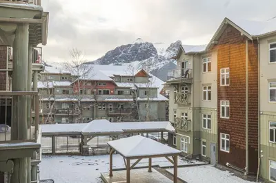 a table on a balcony with snow covered buildings at Cozy 2BR-5BD Suite - Mountain Views - Htd Parking in Canmore