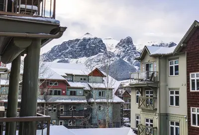 a group of buildings with mountains in the background at Cozy 2BR-5BD Suite - Mountain Views - Htd Parking in Canmore