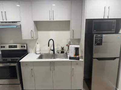 a white kitchen with a sink and a refrigerator at ideal place in Prince George