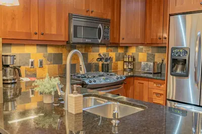 a kitchen with a sink and a stainless steel refrigerator at Rundle Range Retreat Lux Mtn View Condo near dt in Canmore