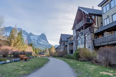 a winding road in front of a building with a mountain at Rundle Range Retreat Lux Mtn View Condo near dt in Canmore