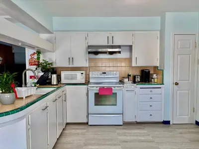 a kitchen with white cabinets and white appliances at Charming Bright 3BR House - Upper Level Suite in Burnaby