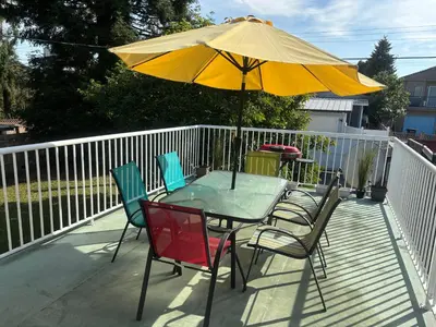 a table and chairs with an umbrella on a deck at Charming Bright 3BR House - Upper Level Suite in Burnaby