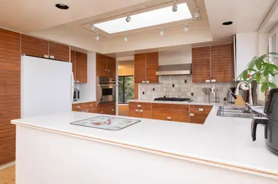 a large kitchen with white countertops and wooden cabinets at Elegant Cypress Park Villa with Panoramic Ocean View in West Vancouver
