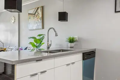 a kitchen with white cabinets and a sink at Stylish & Romantic Riverside Stay in Downtown in Calgary