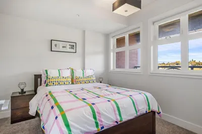 a white bedroom with a bed and two windows at Stylish & Romantic Riverside Stay in Downtown in Calgary