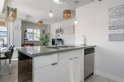 a kitchen with white cabinets and a sink at Cozy And Modern 2 Bedroom Along Bow River in Downtown in Calgary