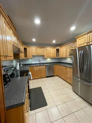 a kitchen with wooden cabinets and a stainless steel refrigerator at Spacious 2 BED close to BEACH, Highway & US BORDER in Surrey