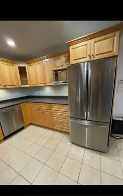 a kitchen with a stainless steel refrigerator and wooden cabinets at Spacious 2 BED close to BEACH, Highway & US BORDER in Surrey