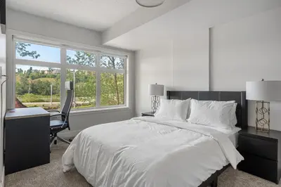 a white bedroom with a bed and a desk and a window at Vibrant Stylish, Cozy Waterfront Downtown in Calgary