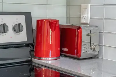 a red appliance sitting on a counter next to a toaster at Vibrant Stylish, Cozy Waterfront Downtown in Calgary
