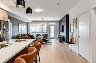 a kitchen and living room with a counter and chairs at Lovely 3BR unit in the heart of Calgary in Calgary