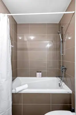 a bathroom with a bath tub and a toilet at Modern 1BR City Escape with Balcony near DT Calgary in Calgary
