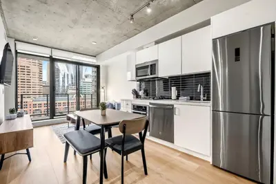 a kitchen with a table and chairs and a refrigerator at Modern 1BR City Escape with Balcony near DT Calgary in Calgary