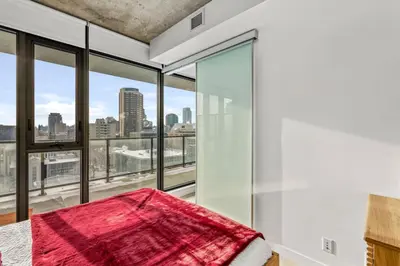 a bedroom with glass windows and a bed with a red blanket at Spacious and Stylish Modern Condo in Calgary in Calgary