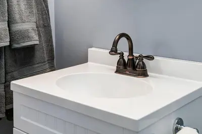 a white bathroom sink with a black faucet at Cozy and Stylish Stay in Mountain View Condo in Canmore