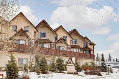 a large house with snow in front of it at Cozy and Stylish Stay in Mountain View Condo in Canmore