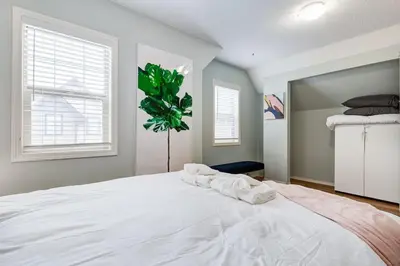 a large white bed in a room with two windows at The Cutest Condo in Canmore and Banff in Canmore