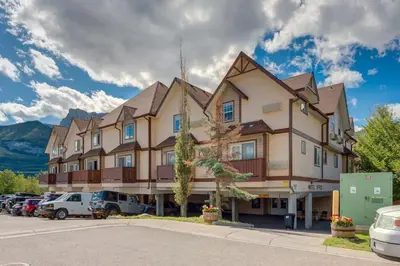 a large building with cars parked in a parking lot at The Cutest Condo in Canmore and Banff in Canmore