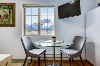 a table and two chairs in a room with a window at Cozy Mountain View Condo Close to DT Canmore in Canmore