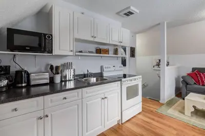 a kitchen with white cabinets and a sink and a microwave at Cozy Mountain View Condo Close to DT Canmore in Canmore