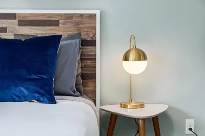 a bed with a blue pillow and a gold lamp at Stunning Mountain View Cozy Studio for Small Grp in Canmore