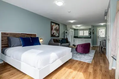 a bedroom with a large white bed and a living room at Stunning Mountain View Cozy Studio for Small Grp in Canmore