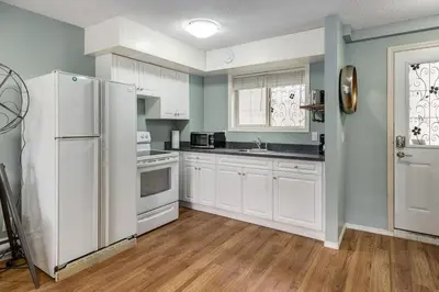 a kitchen with white cabinets and a white refrigerator at Stunning Mountain View Cozy Studio for Small Grp in Canmore