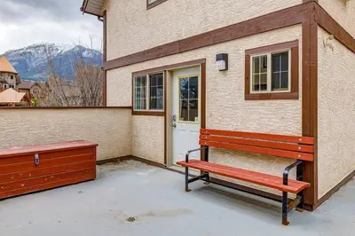 a red bench sitting outside of a building with a door at Charming and Stylish renovated Condo near Banff in Canmore
