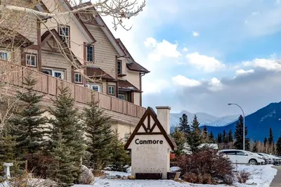 a sign in front of a house in the snow at Charming Condo In The Heart Of Canmore in Canmore