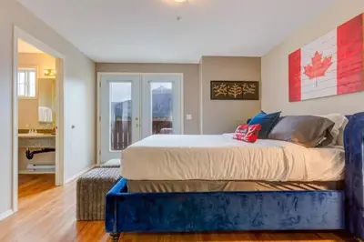 a bedroom with a king sized bed with a blue bench at Cozy Condo in the Heart of Canmore in Canmore