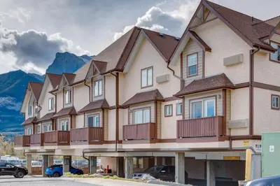 a large building with cars parked in a parking lot at Delightful 2BR Mountain Escape in Canmore in Canmore