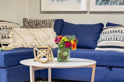 a blue couch with a vase of flowers on a table at Delightful 2BR Mountain Escape in Canmore in Canmore