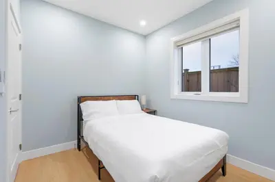 a white bedroom with a bed and a window at Modern 6BR Home - Perfect for Groups & Families in Vancouver