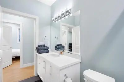 a white bathroom with a sink and a toilet at Modern 6BR Home - Perfect for Groups & Families in Vancouver