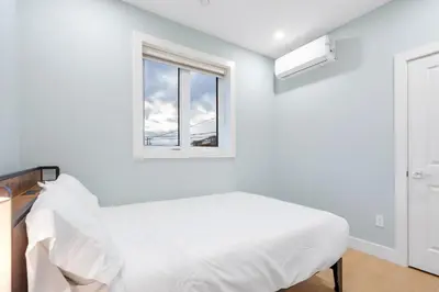a white bedroom with a bed and a window at Modern 6BR Home - Perfect for Groups & Families in Vancouver