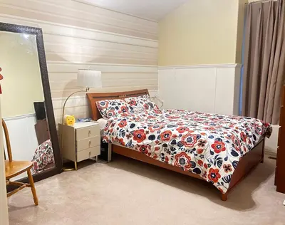 a bedroom with a bed with a comforter and a mirror at Luxury & Spacious three bedrooms House Near Coquitlam Town Centre in Coquitlam
