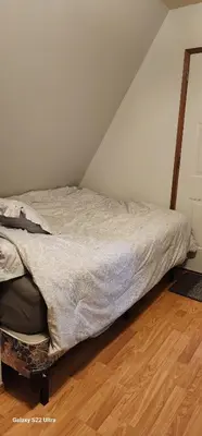 a unmade bed in a room with a wooden floor at Brown Family Farm in Grand Forks