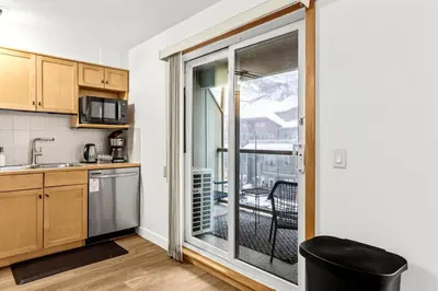a kitchen with a sliding glass door leading to a balcony at Mesmerizing 2BR Retreat Made For You in Canmore